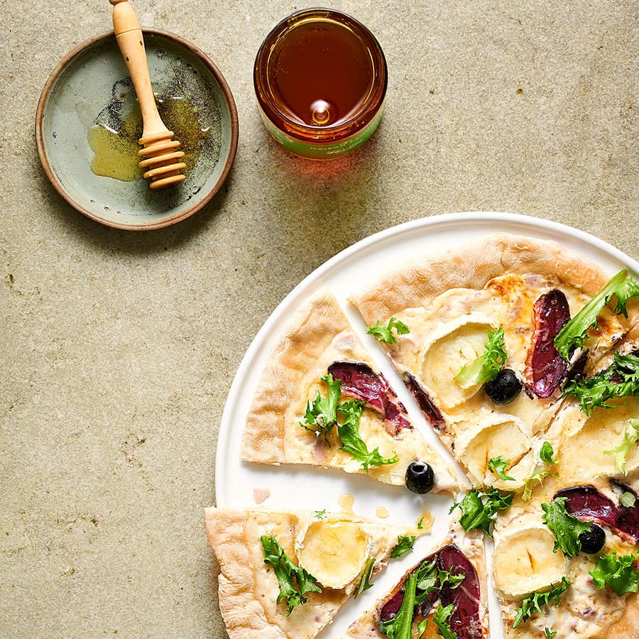 Pizza chèvre miel coupée en parts.