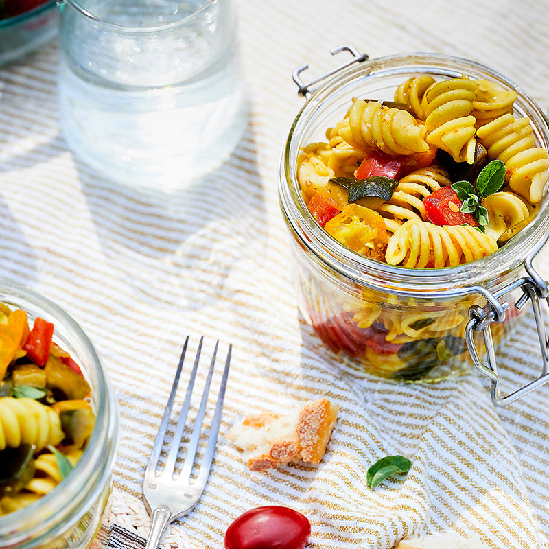 Salade de pâtes et légumes d'été sur une nappe de pique-nique.
