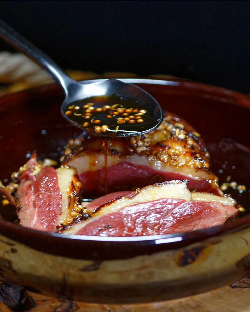 Plat avec le magret de canard tranché et sa sauce au miel et aux épices.