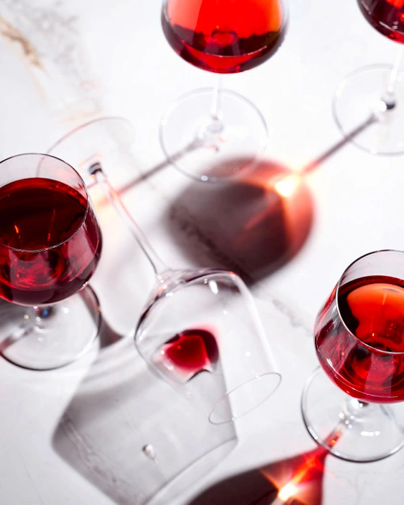Plusieurs verres avec du jus de raisin rouge sur une nappe blanche.