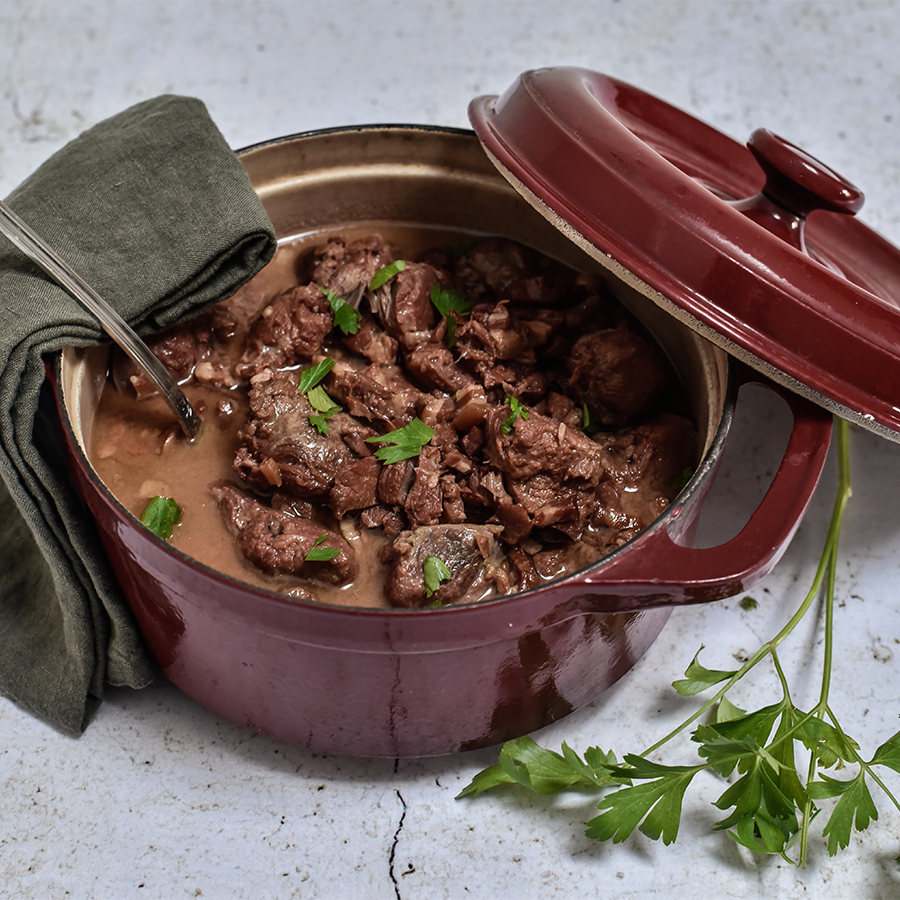 Joue de porc à la bière et au miel mijotée dans une cocotte en fonte rouge.