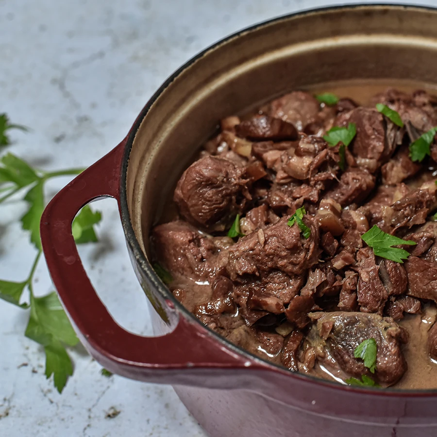 Joue de porc fondante à la bière et au miel, servie dans une cocotte rouge.