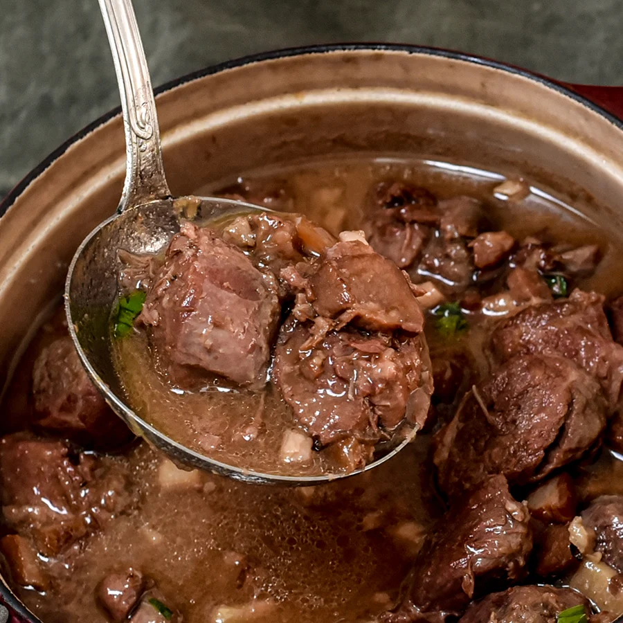 Détail de la sauce à la bière et au miel nappant la joue de porc, avec une louche.