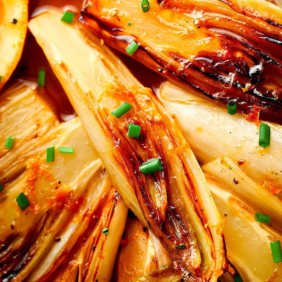 Endives braisées au miel et à l’orange servies avec ciboulette.