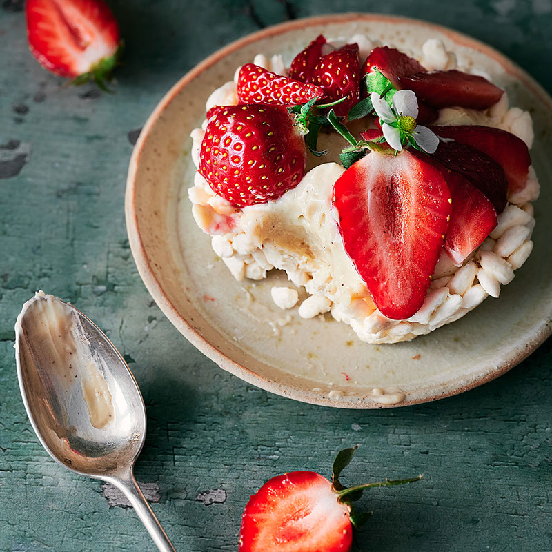 Tartelette aux fraises entamée dans une assiette avec une cuillère portant quelques traces de crème miel & noisette.